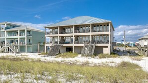 A multi-story beach house with a flat roof, multiple balconies, and a staircase leading to the upper levels. - Luxurious Beachfront End Unit Townhome |Unobstructed Gulf Views |Step onto Sugar White Sands |Garage (Navarre Beach)