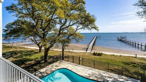 A pool area with a view of the beach and the sea.