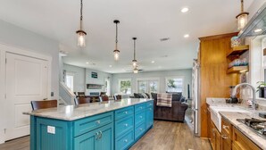 A spacious kitchen with a large island, teal cabinetry, and a wooden countertop.
