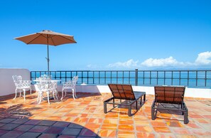 A terrace with a table and chairs, a large umbrella, and a view of the sea. - Luxurious retreat with Private Pool & Modern Mexican Charm! 2BD Condo for rent i (Puerto Vallarta)