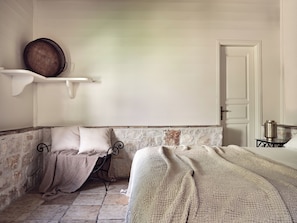 Ein Zimmer mit einem Bett, einem Sessel, einem Regal mit einem Korb und einer Tür.