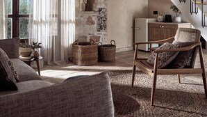 Una sala de estar acogedora con una pared de piedra, una escalera de madera y vistas al exterior.