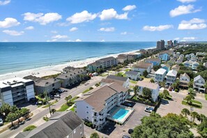 A coastal residential area with a beachfront, multi-story buildings, and a swimming pool.