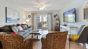 A living room with a sofa, chairs, a coffee table, a TV, and a bookshelf. - *Fall into Savings-20% Off New Bookings thru 2026* (Surfside Beach)