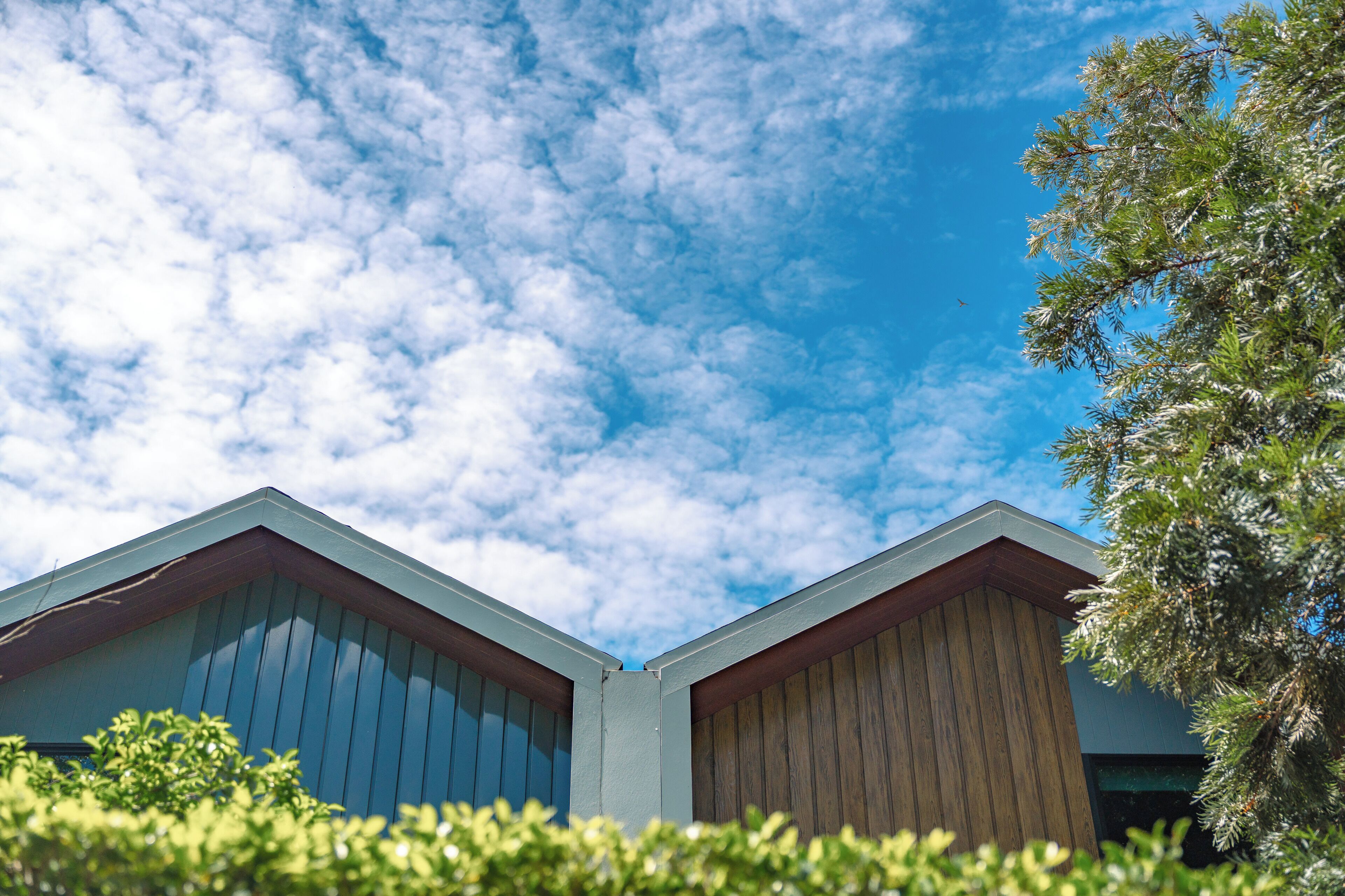 A building with a sloped roof and a corner view of the sky.