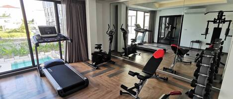 A modern gym with cardio machines, weightlifting equipment, and a large mirror.
