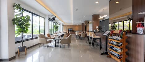 Un restaurante amplio y bien iluminado, con techos altos, ventanas grandes y diferentes opciones de asientos.
