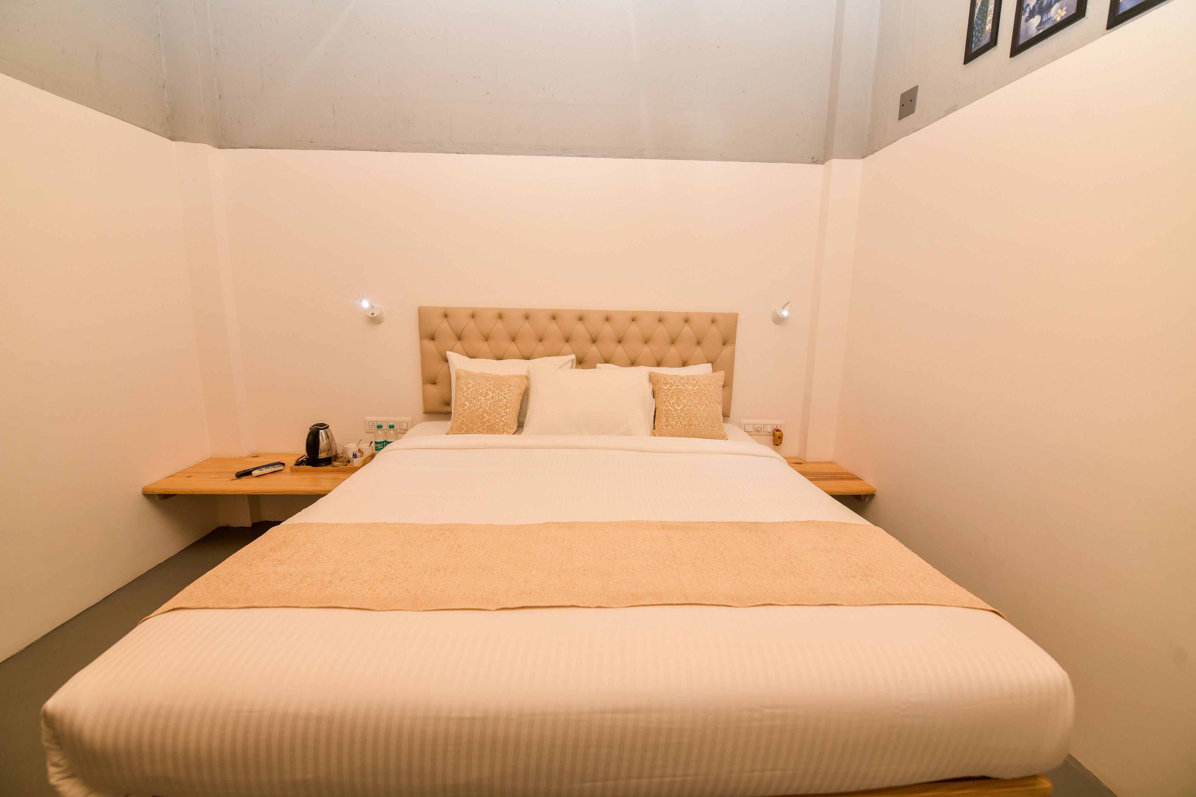 A neatly arranged hotel room with a large bed, a wooden nightstand, and a wall-mounted light fixture.