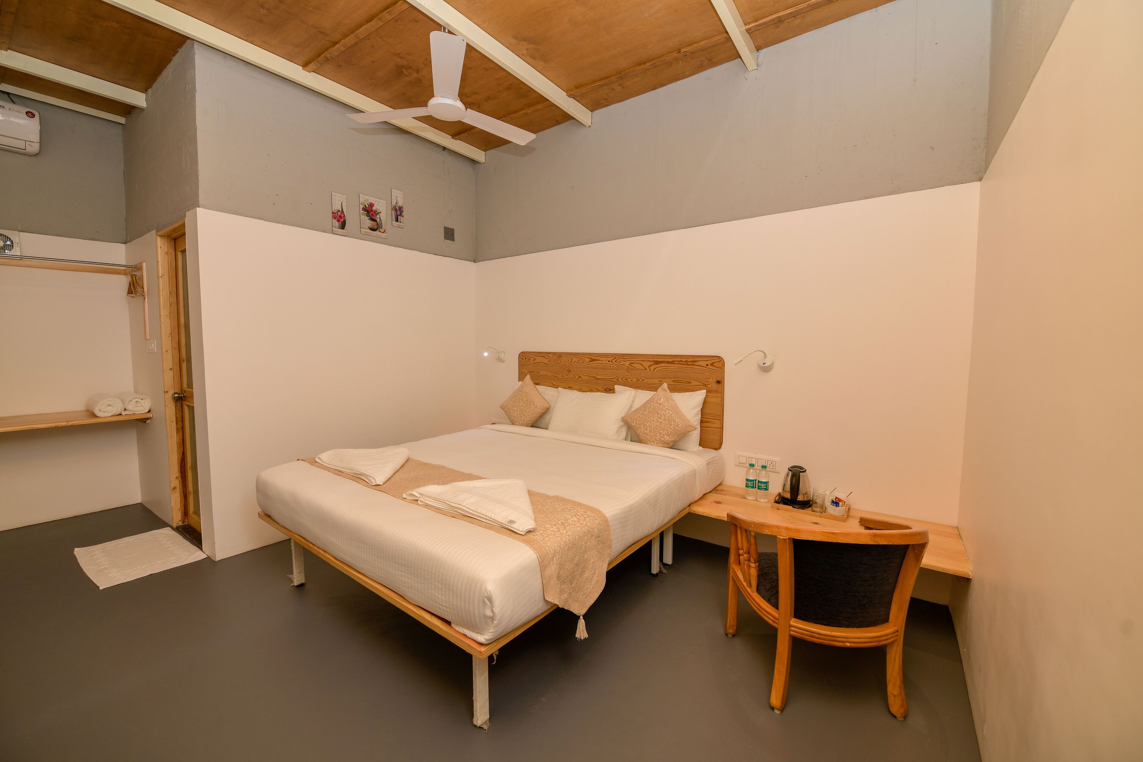 A bedroom with a bed, bedside table, chair, and a ceiling fan.