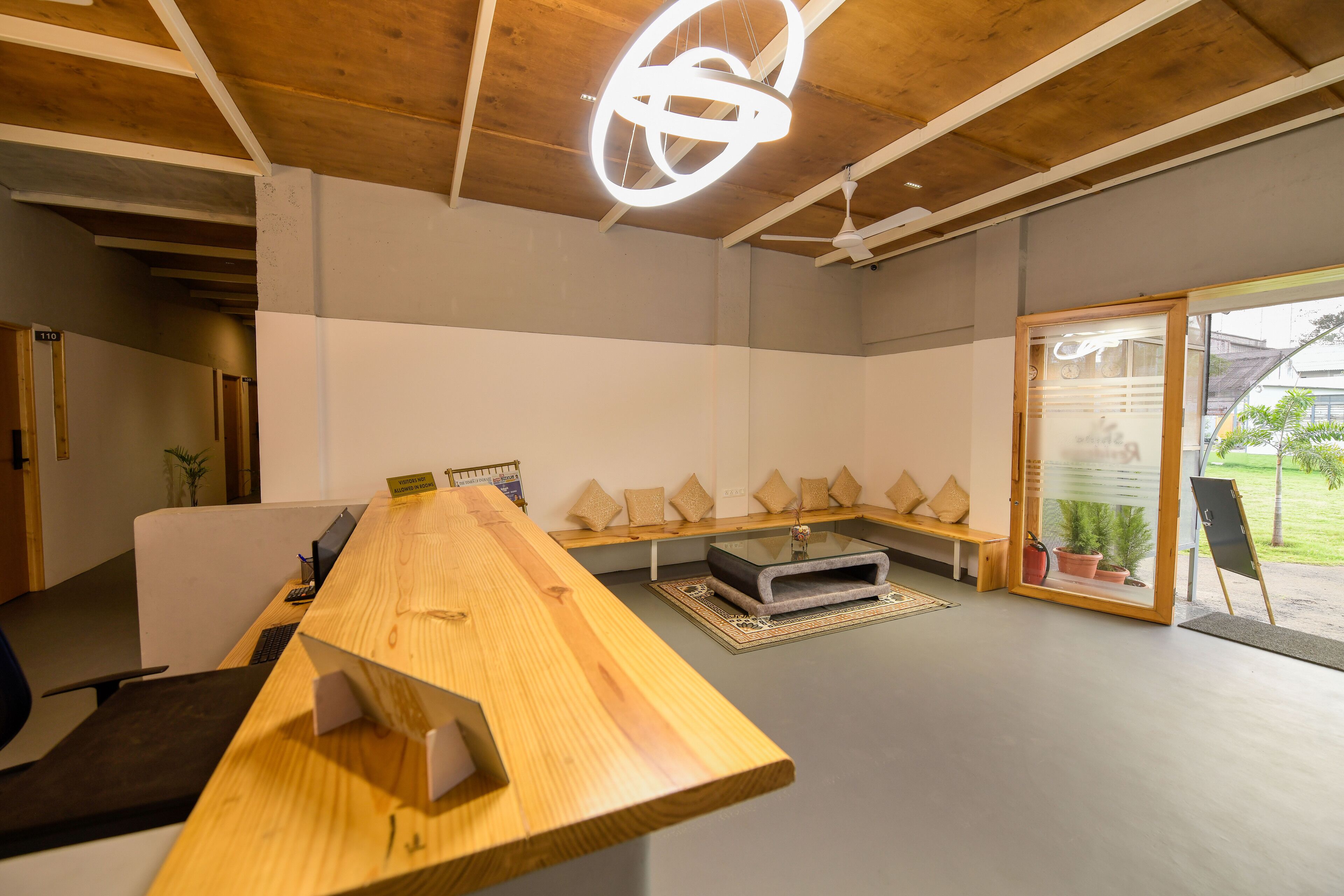 A modern meeting room with a long wooden table, a bench, and a glass partition.