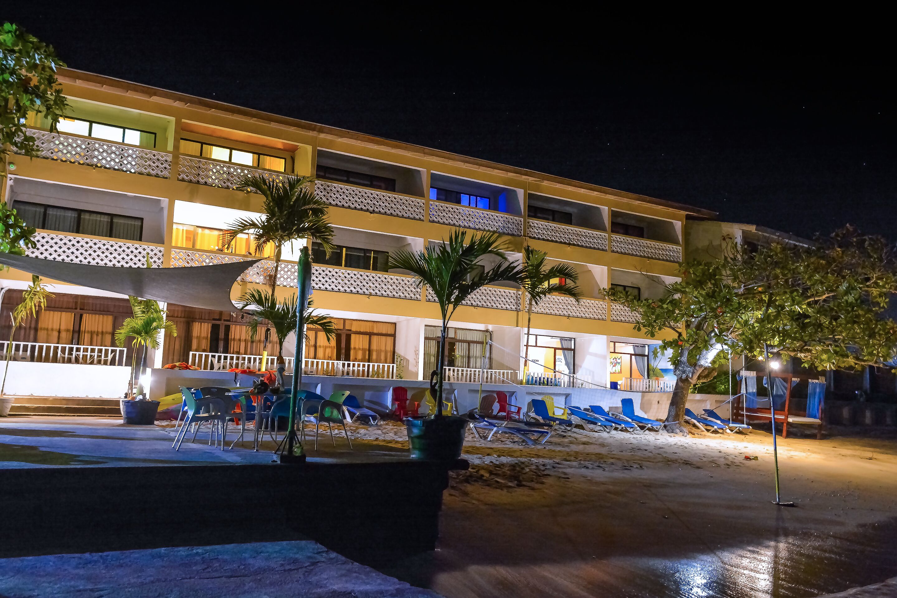 A hotel with multiple balconies, outdoor seating, and palm trees.