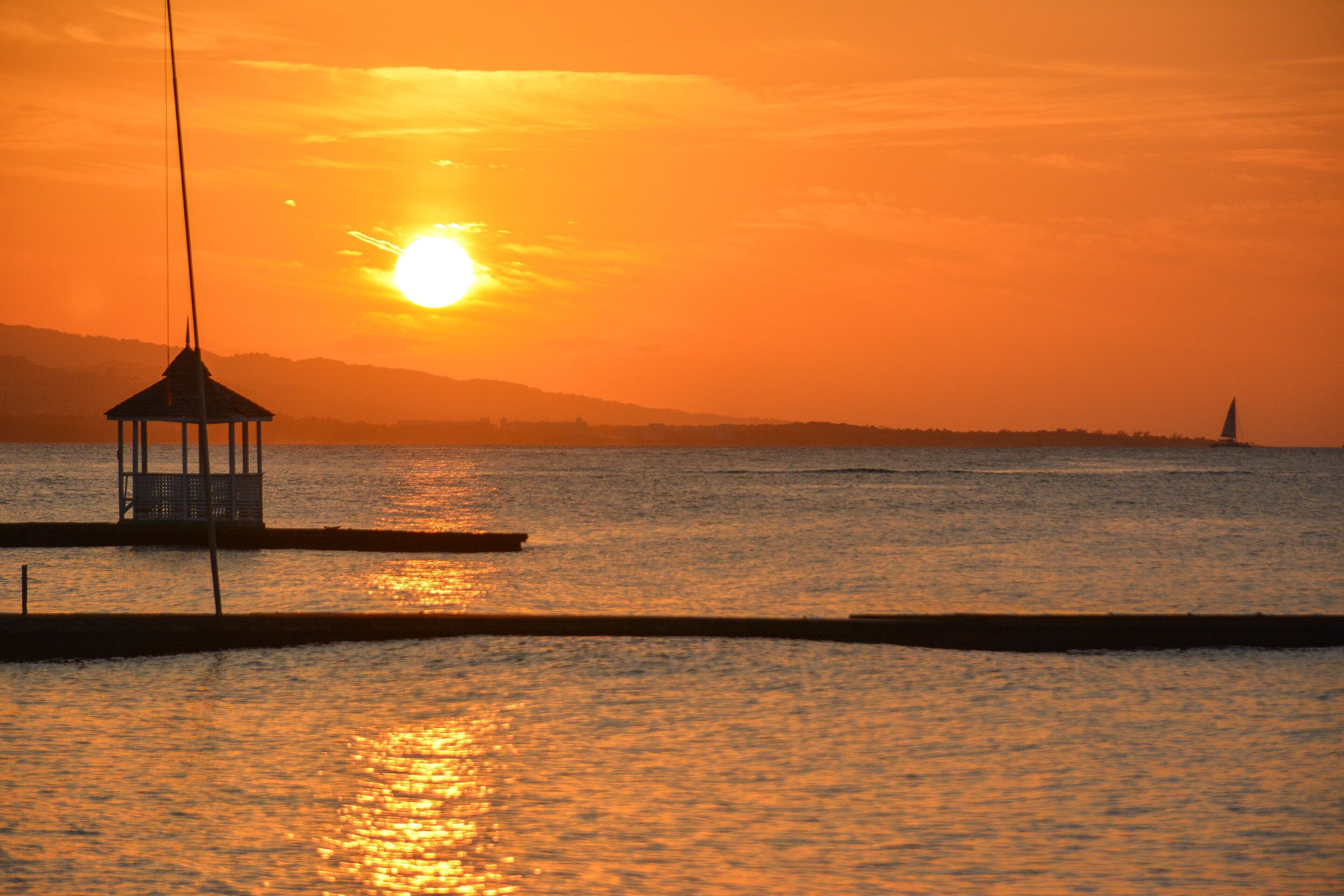 Un pabellón en un muelle con un atardecer de fondo.