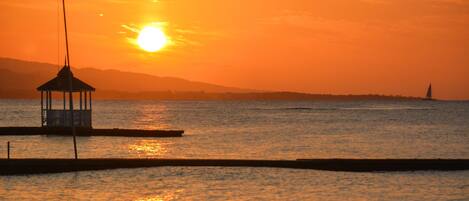 Un pabellón en un muelle con un atardecer de fondo.