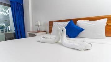 A neatly made bed with white and blue pillows, a wooden headboard, and a white towel folded on the bed.