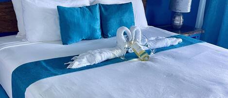 A neatly made bed with white linens, blue pillows, and a blue bedspread.