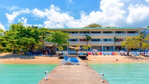 Une jetée qui mène à une plage, avec un hôtel en arrière-plan.