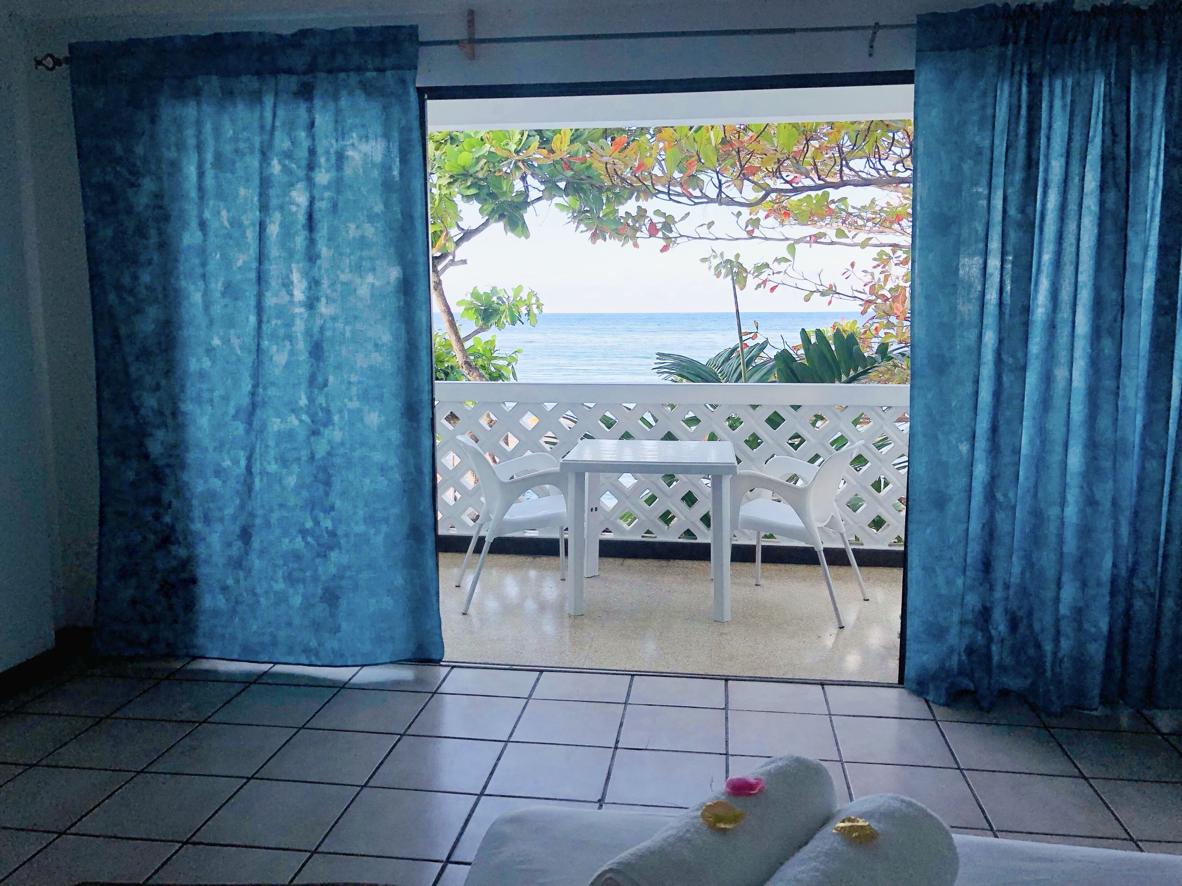 Una habitación con vista al mar, una mesa blanca y dos sillas.