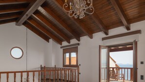 Ein Schlafzimmer mit Holzboden, einer Kristallleuchtre, einem Balkon mit Aussicht und einem Bett.