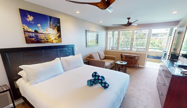 A hotel room with a large bed, a desk, a chair, a sofa, and a TV.