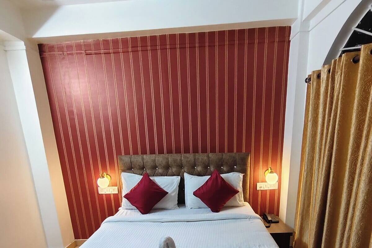 A neatly made bed with a swan-shaped towel, two red pillows, and a headboard with vertical stripes.