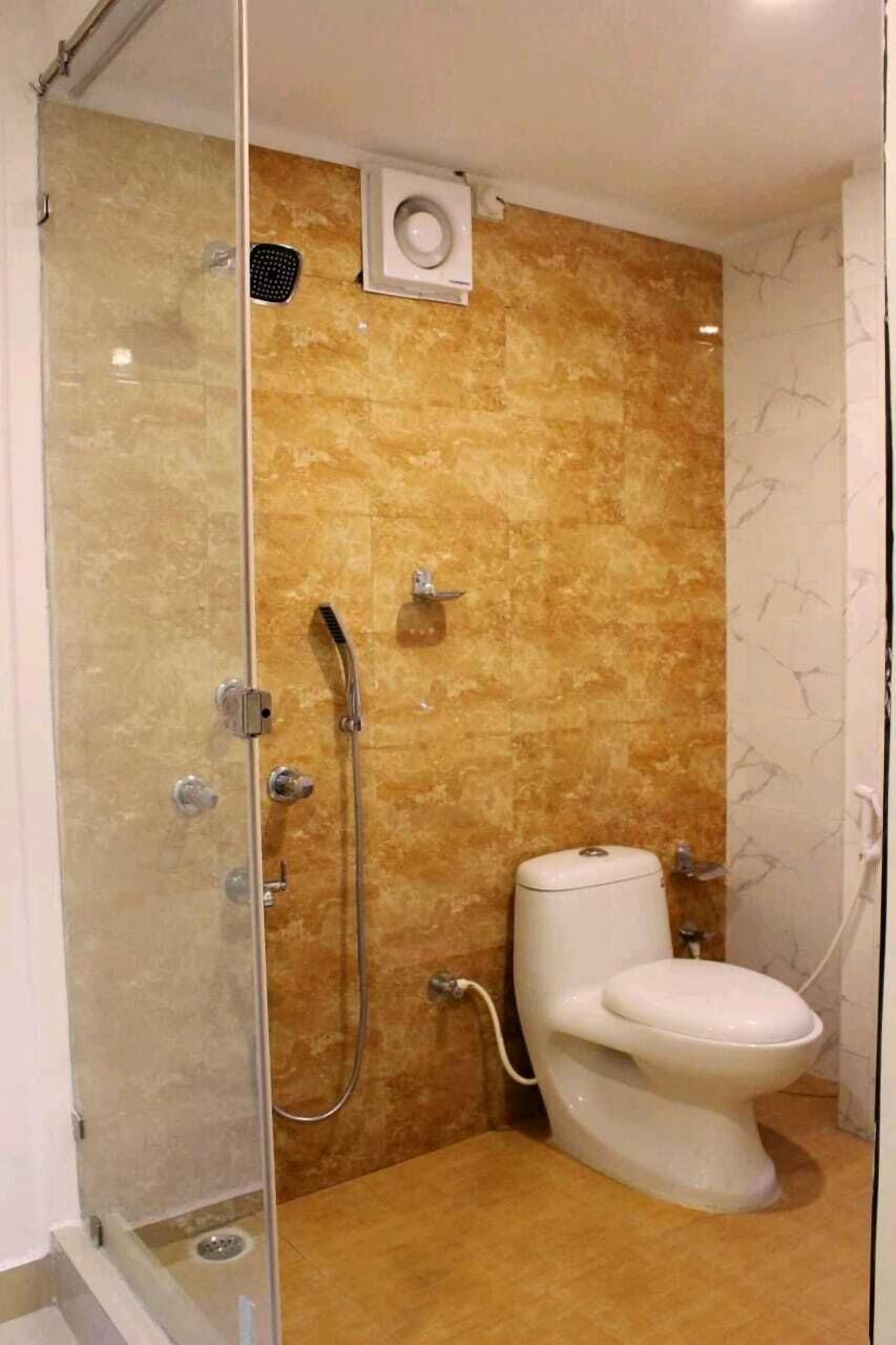 A modern bathroom with a glass-enclosed shower, a white toilet, and a marble-tiled wall.
