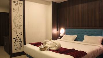 A hotel room with a large bed, a wooden headboard, a decorative wall panel, and a bedside table with a lamp.