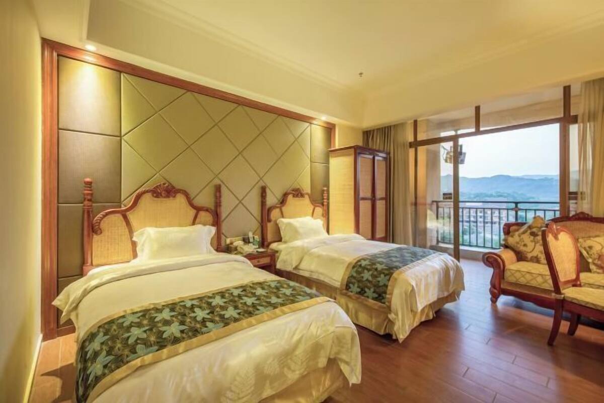 A hotel room with two beds, a sofa, and a balcony with a view.