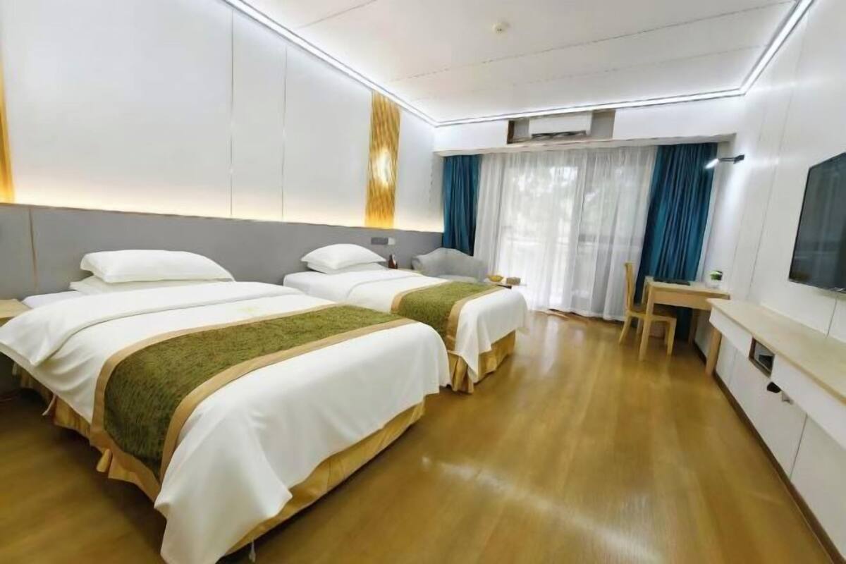 A hotel room with two beds, a desk, and a television.