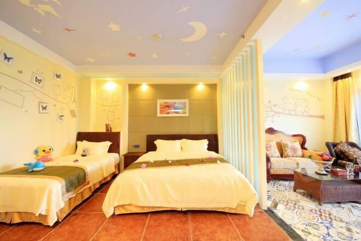 A hotel room with two beds, a sofa, and a dining area.