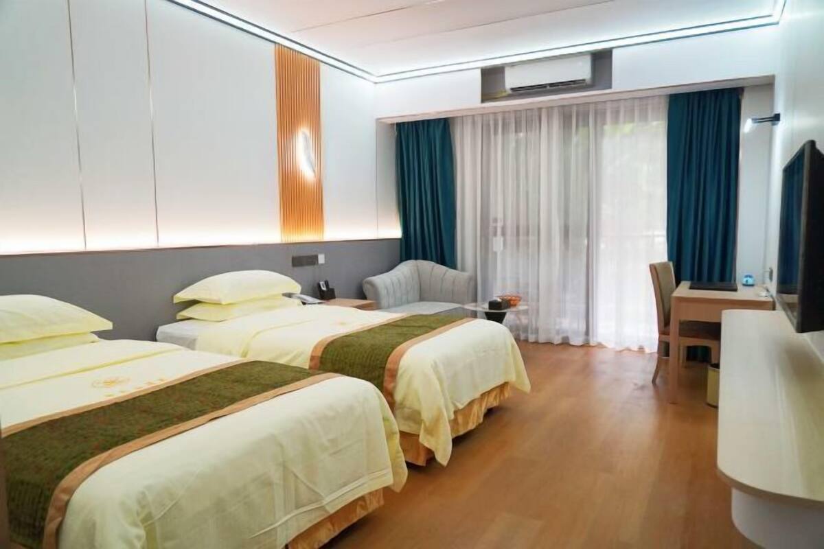 A hotel room with two beds, a desk, a chair, and a TV.