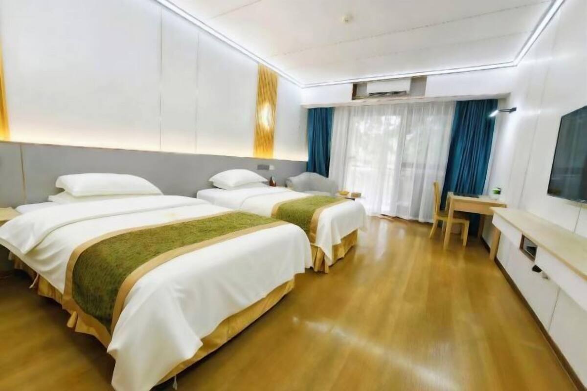 A hotel room with two beds, a desk, and a chair.