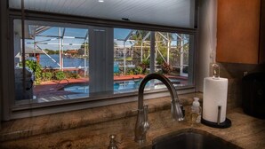 Cocina con un amplio ventanal que da a una piscina y zona exterior.