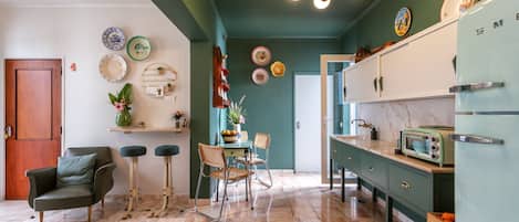A kitchen with a green ceiling, a wooden door, and a vintage refrigerator.