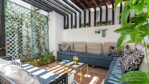 A cozy outdoor seating area with a blue sofa, striped cushions, and a wicker chair. - Downtown Alegria (Tavira)