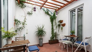 A patio with a wooden table, chairs, and potted plants. - Downtown Alegria (Tavira)