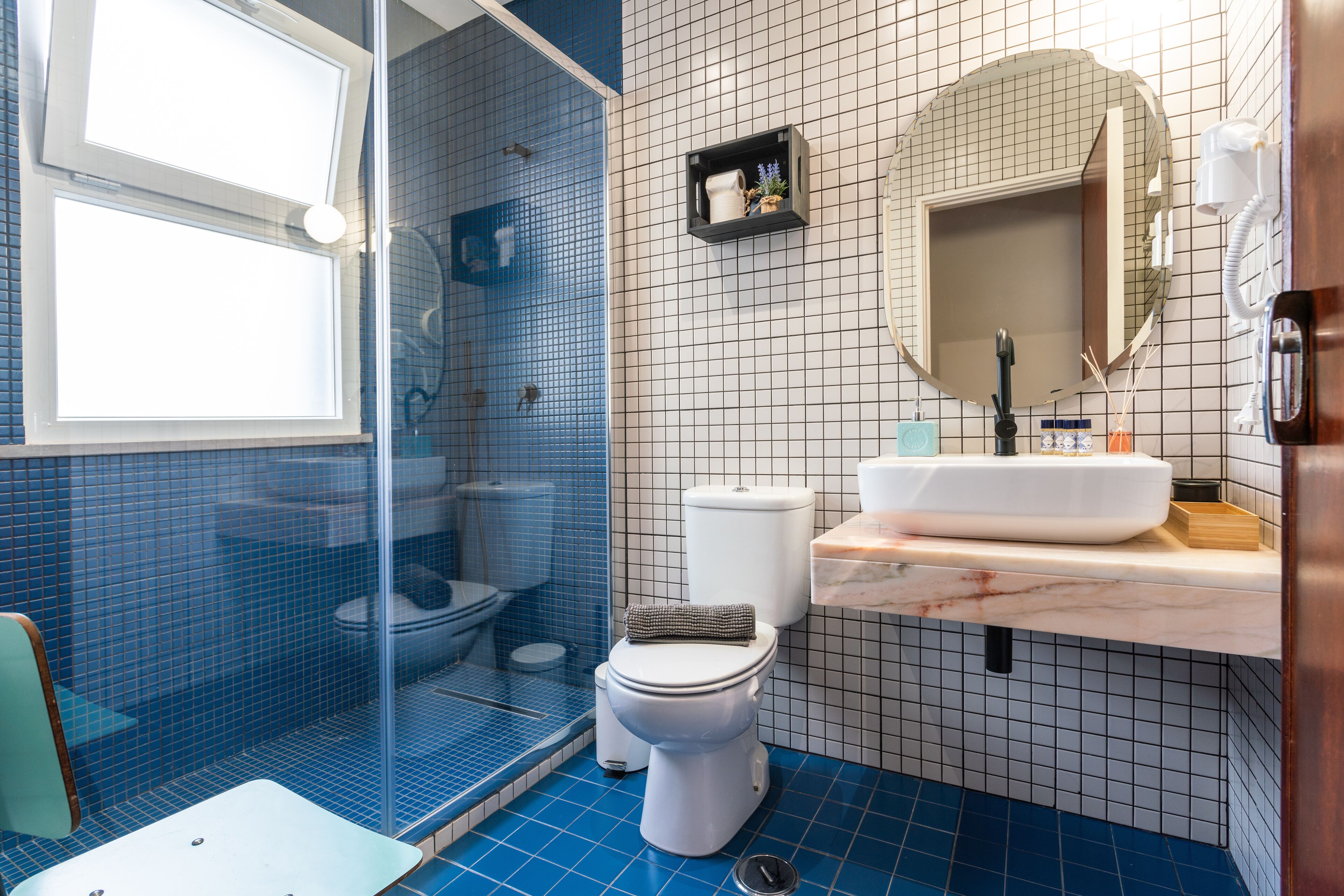 A bathroom with a shower, toilet, sink, and a mirror.