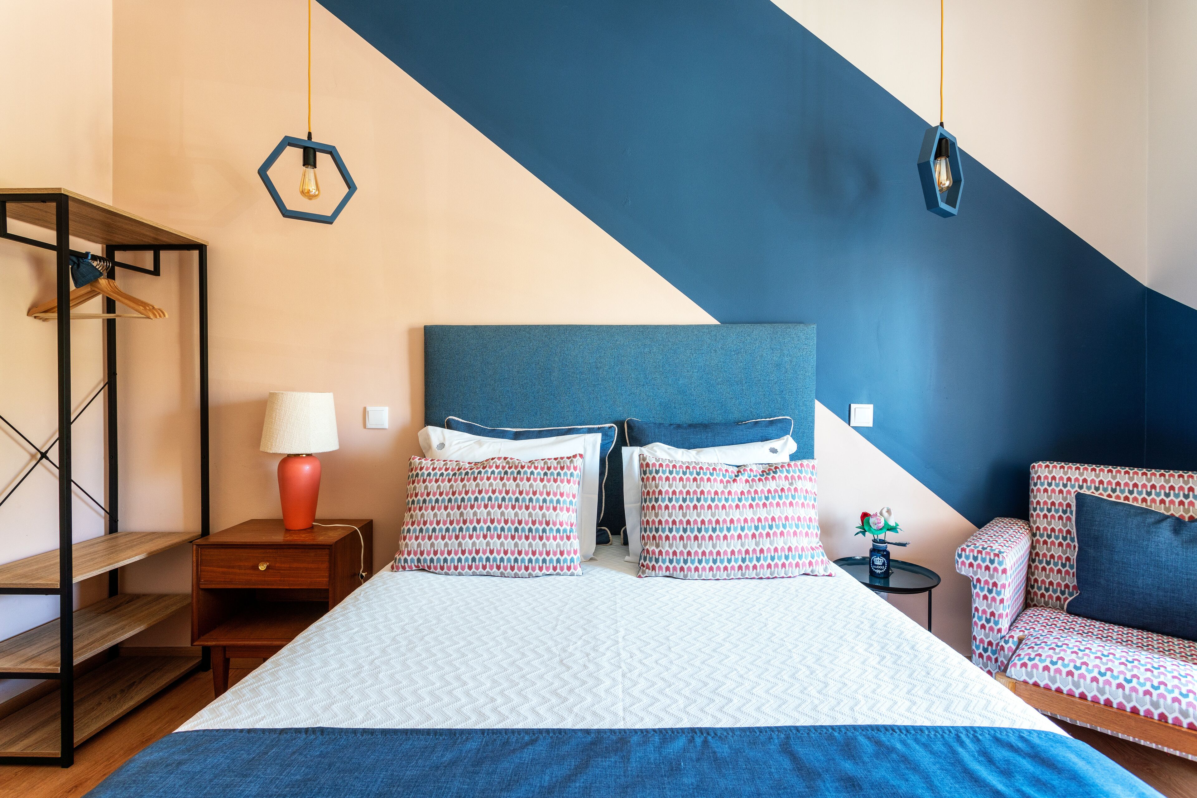 Una camera da letto con un letto, due comodini, una lampada da comodino, una sedia e un lampadario.