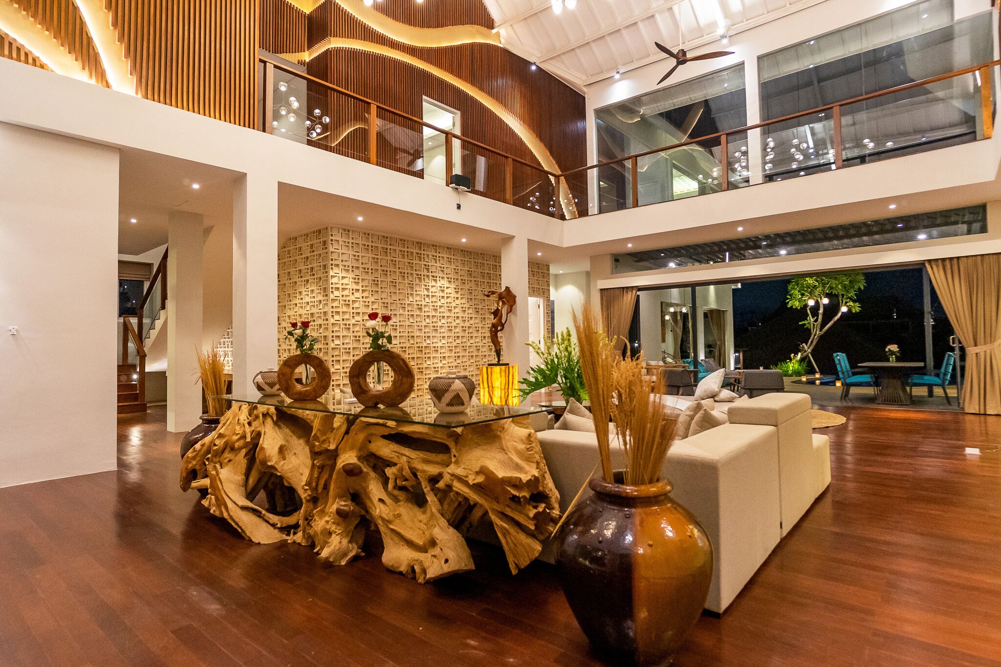 A spacious living area with a high ceiling, a central wooden coffee table, and a seating area with sofas.