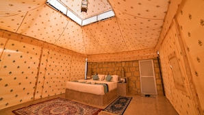 A room with a bed, a nightstand, a stone wall, and a skylight. - Desert Over Night Camp & Resort (Jaisalmer)