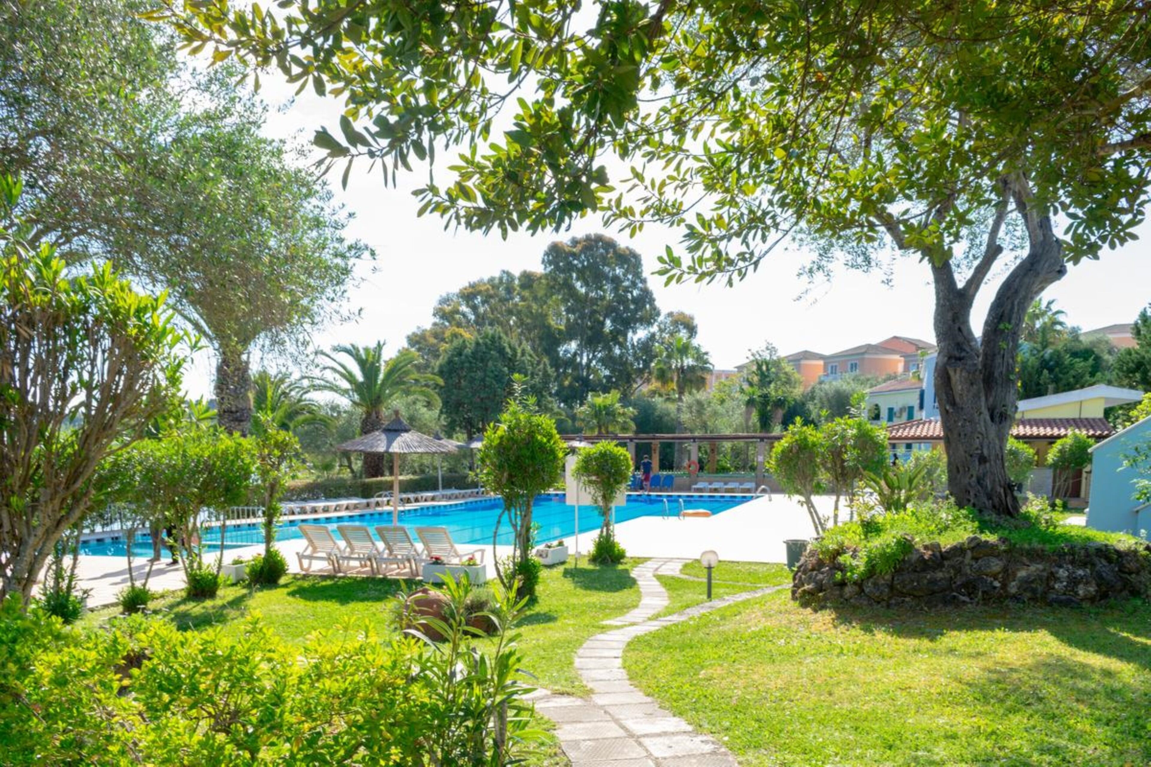 A pool area with lounge chairs, a pathway, and surrounding greenery.