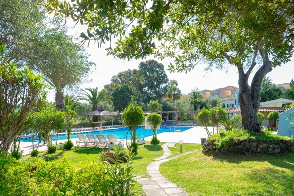 A pool area with lounge chairs, a pathway, and surrounding greenery.