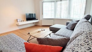 A modern living room with a sofa set, a coffee table, and a flat-screen TV.