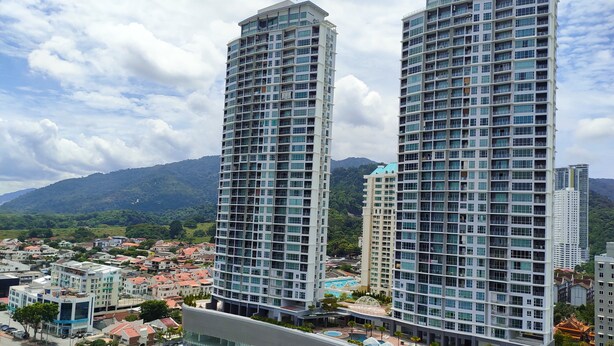 Deux immeubles de grande hauteur qui offrent une vue sur un quartier résidentiel et sur des montagnes en arrière-plan.