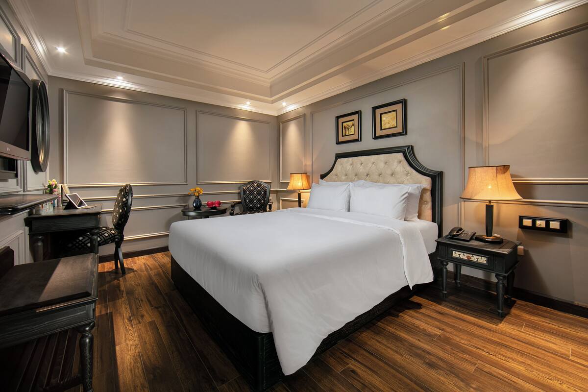 Une chambre d’hôtel avec un grand lit, un bureau, une chaise et un téléviseur.