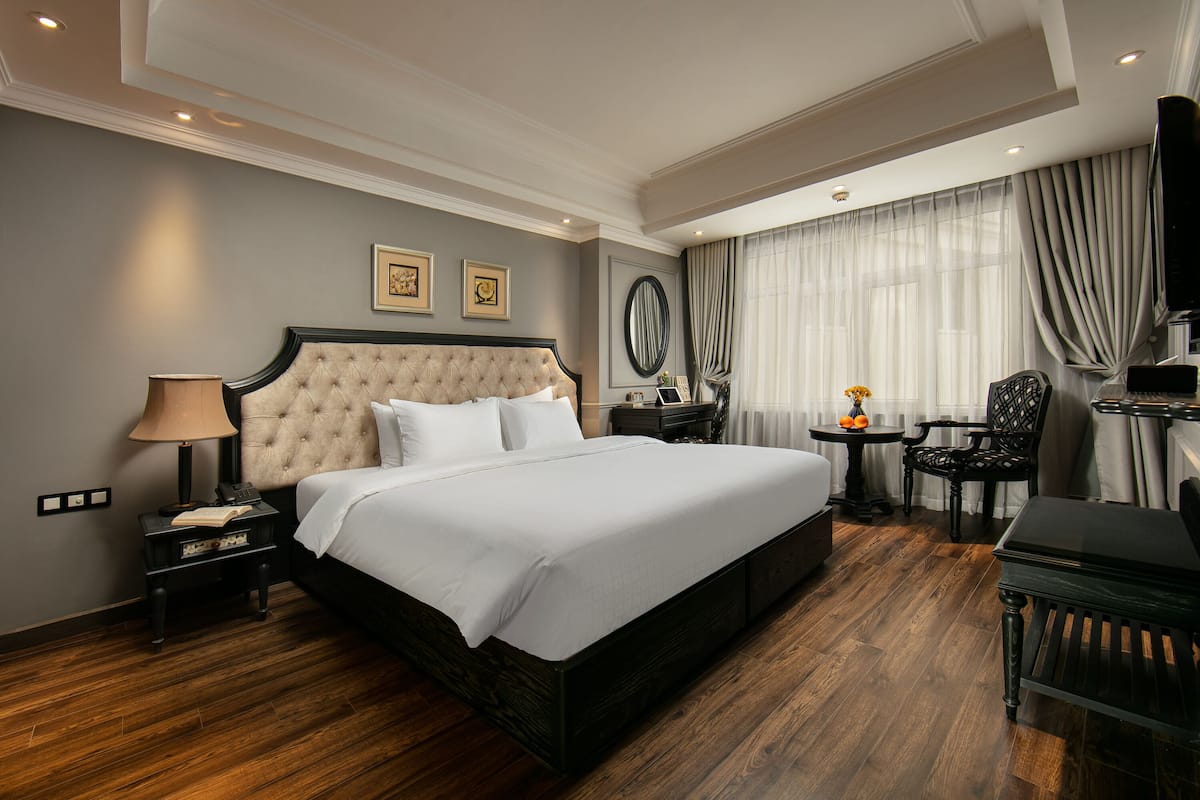 Une chambre d’hôtel avec un grand lit, un bureau, une chaise et un téléviseur.