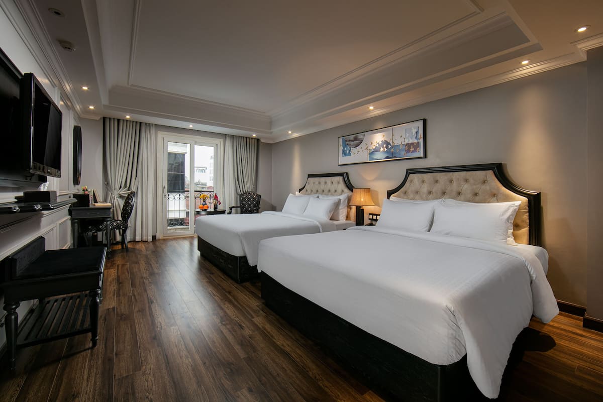 Une chambre d’hôtel avec deux lits, une télévision, un bureau et un balcon avec vue.