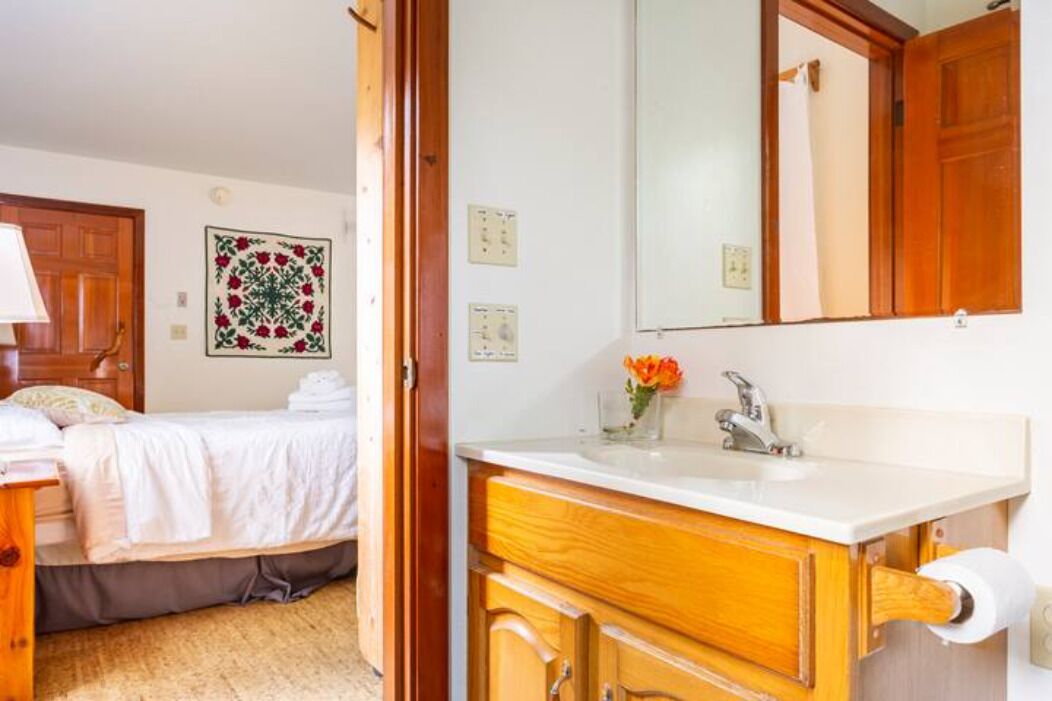 Une chambre d’hôtel avec un lit, une coiffeuse en bois dotée d’un lavabo et un grand miroir.