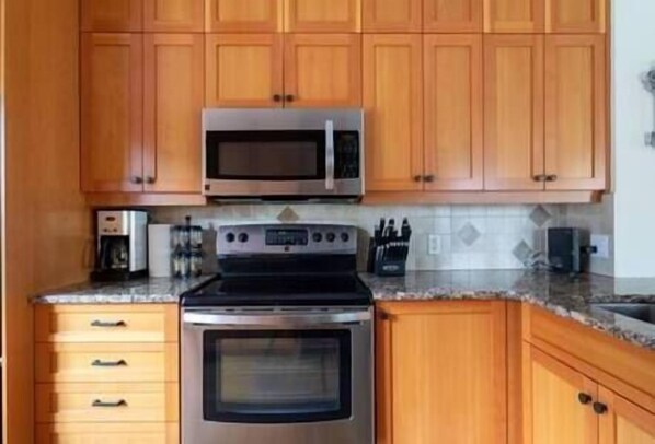 A kitchen with wooden cabinets, a microwave, a stove, and a coffee maker.