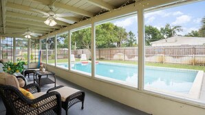 A covered patio with a pool, wicker furniture, and a view of the backyard. - Thai · Cozy Ginger Home with Pool · 12 minutes to Beach · Pet-Friendly (Melbourne)