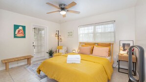 A bedroom with a bed, bedside table, lamp, and a ceiling fan. - Thai · Cozy Ginger Home with Pool · 12 minutes to Beach · Pet-Friendly (Melbourne)